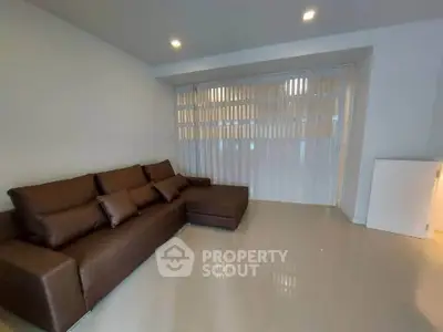 Spacious living room with modern brown sofa and sleek tile flooring