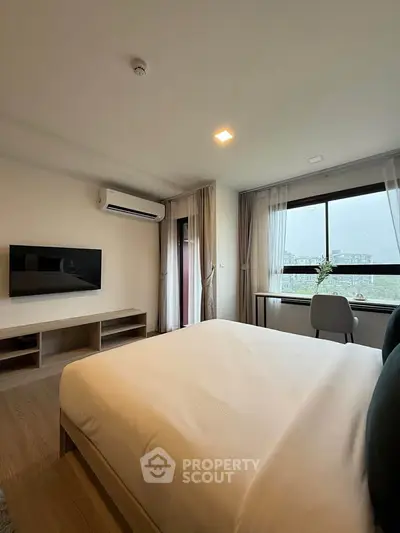 Modern bedroom with large window and air conditioning, featuring a sleek TV and cozy workspace.