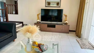 Charming living room with modern decor and large TV, perfect for relaxation and entertainment.