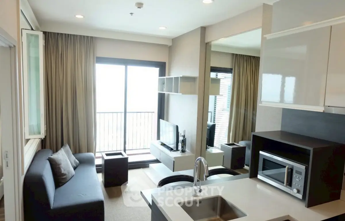 Modern living room with balcony, featuring sleek kitchen and cozy seating area.