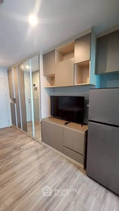 Modern living room with sleek cabinetry and flat-screen TV, featuring stylish wood flooring and contemporary design.