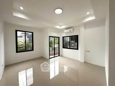 Spacious living room with large windows and balcony access, featuring modern lighting and sleek tile flooring.