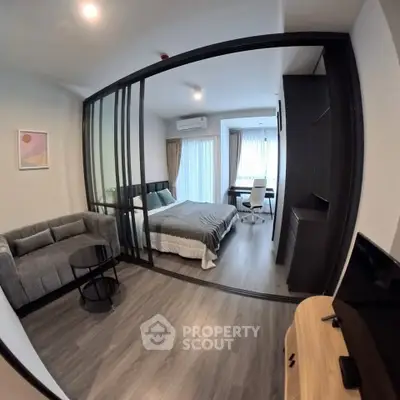 Modern studio apartment with glass partition, cozy living area, and stylish bedroom.