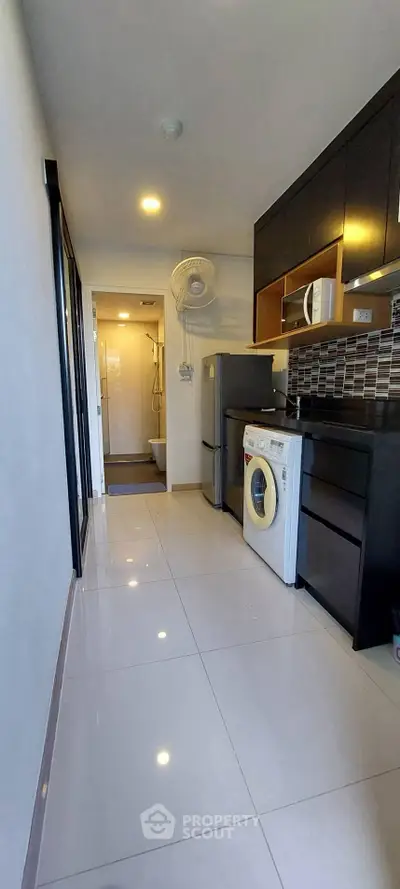 Modern kitchen with sleek appliances and glossy tiles in a compact layout