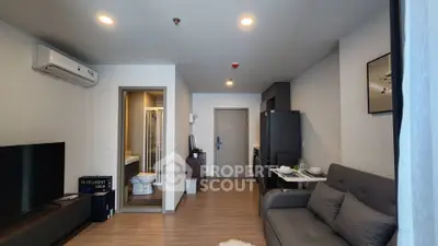 Modern living room with open layout, featuring sleek furniture and integrated kitchen area.