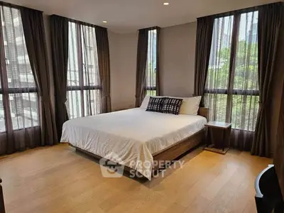 Spacious bedroom with large windows and elegant curtains in a modern apartment.