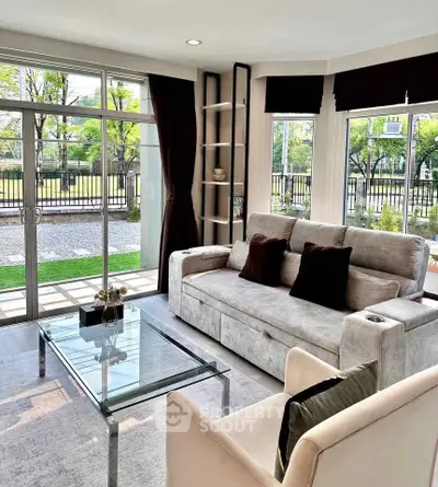 Modern living room with large windows and stylish furniture, offering a bright and inviting atmosphere.