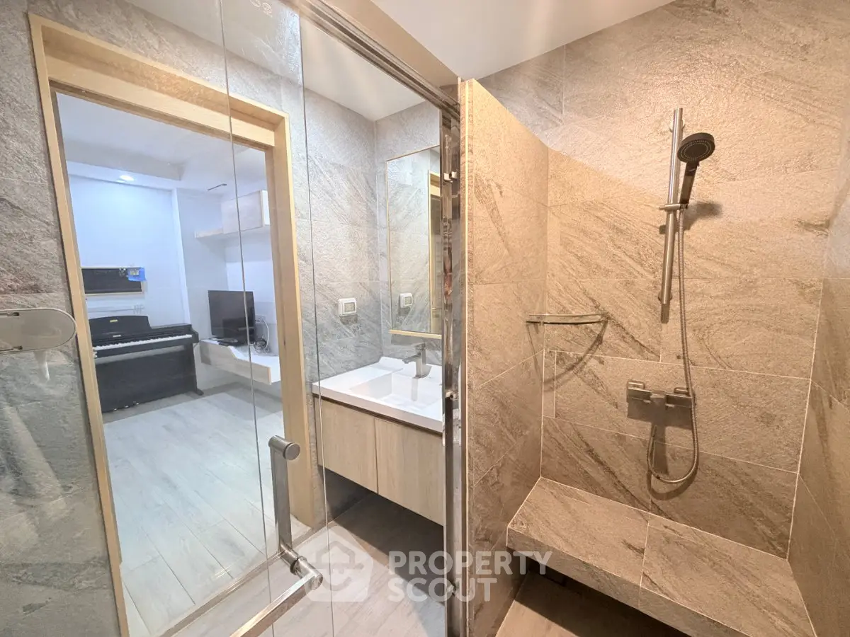 Modern bathroom with glass shower and view into living area