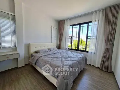 Spacious bedroom with large window and elegant curtains, offering a serene and bright atmosphere.