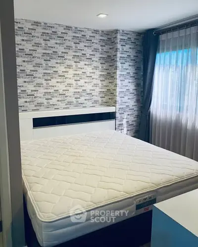Cozy bedroom with modern brick accent wall and large window for natural light.
