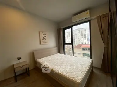 Modern bedroom with large window and city view, featuring a comfortable bed and stylish decor.