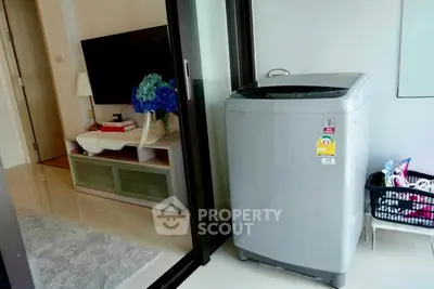 Modern living room with washing machine and TV, ideal for compact urban living.