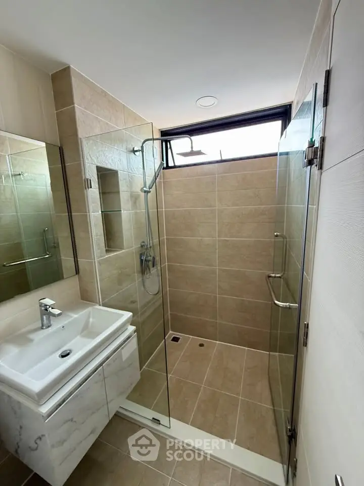 Modern bathroom with glass shower and sleek sink in contemporary apartment.