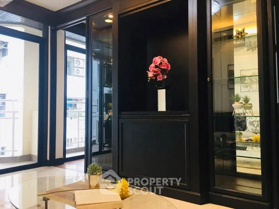 Elegant living room with glass cabinets and balcony view, perfect for modern urban living.