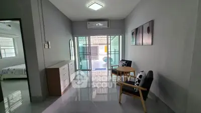 Modern living room with sleek furniture and large glass doors leading to a balcony.
