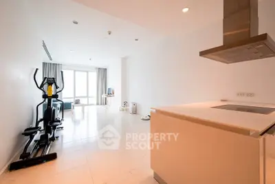 Spacious modern living area with exercise equipment and sleek kitchen design.