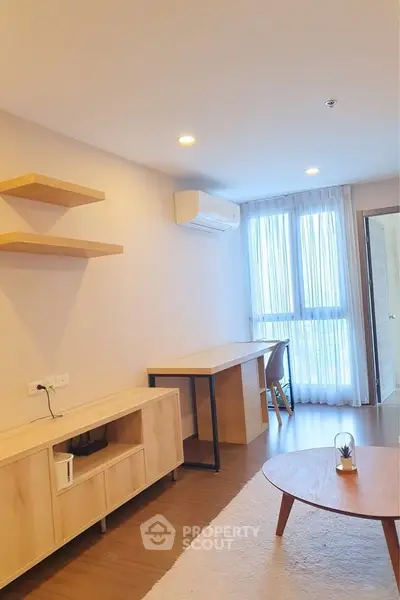 Modern living room with stylish furniture and natural light, featuring a cozy workspace and air conditioning.