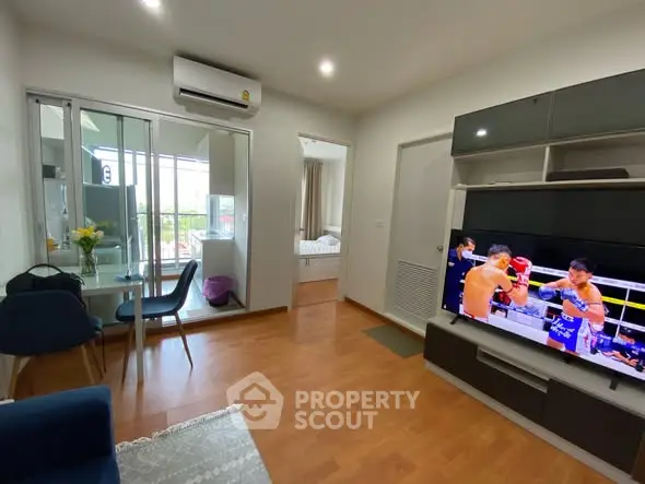 Modern living room with wooden flooring, TV, and dining area in a stylish apartment.