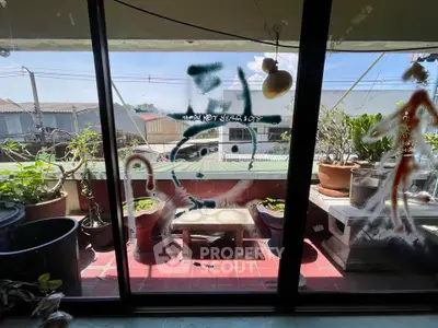 Charming balcony with potted plants and artistic window design, perfect for relaxation.