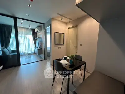 Modern apartment interior with dining area and view into bedroom, featuring sleek design and natural light.
