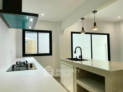 Modern kitchen with sleek design, featuring gas stove and stylish lighting, perfect for culinary enthusiasts.
