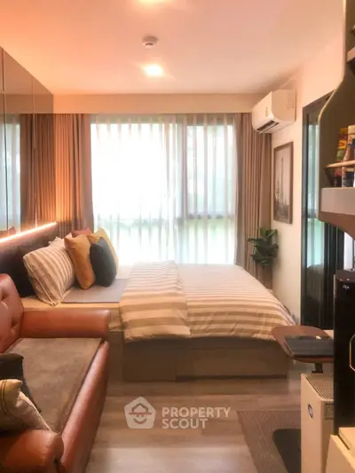 Cozy bedroom with modern decor, featuring a comfortable bed, stylish sofa, and natural light from large windows.