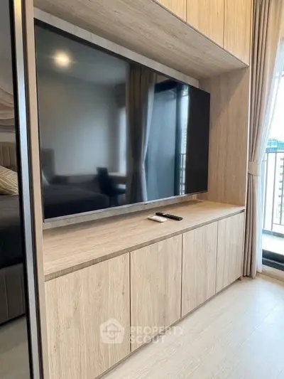 Modern living room with sleek TV unit and large window offering natural light.