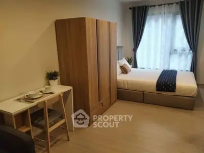 Cozy studio apartment with bed, wardrobe, and dining area near window with curtains.