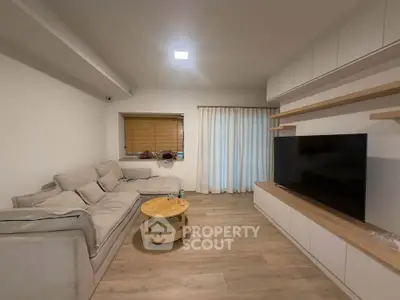 Modern living room with cozy sofa, large TV, and stylish wooden accents.