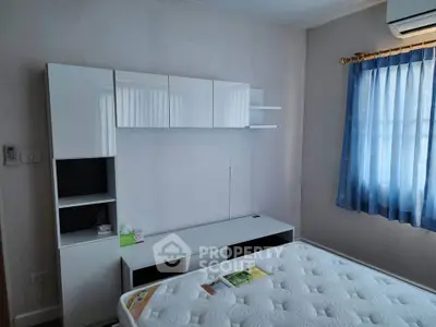 Cozy bedroom with modern white furniture and blue curtains, featuring a comfortable mattress and air conditioning.