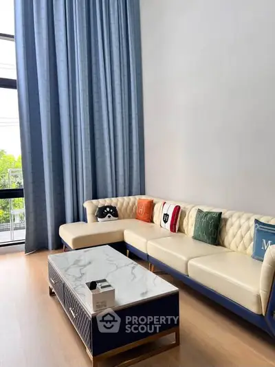 Stylish living room with modern sofa and marble coffee table, featuring floor-to-ceiling windows and elegant curtains.