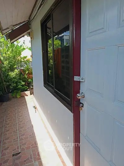 Charming exterior corridor with tiled flooring and lush greenery