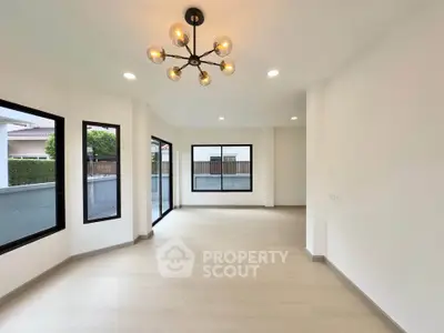 Spacious modern living room with large windows and stylish chandelier