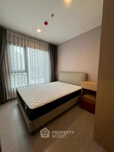 Modern bedroom with large window and city view, featuring a comfortable bed and stylish decor.