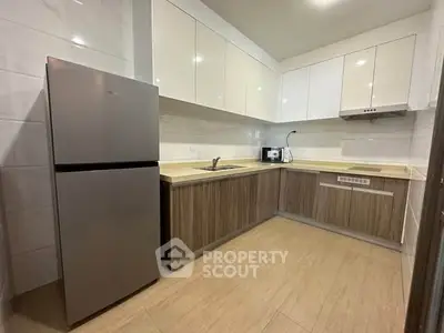 Modern kitchen with sleek cabinetry and stainless steel fridge in a contemporary apartment.