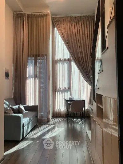 Elegant living room with high ceilings and large windows, featuring modern furniture and abundant natural light.