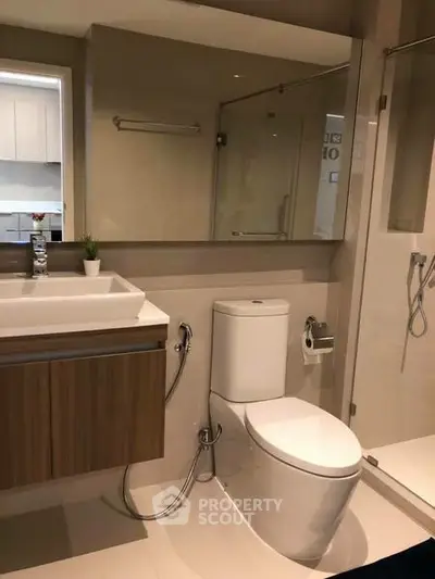 Modern bathroom with sleek fixtures and glass shower enclosure in a contemporary home.