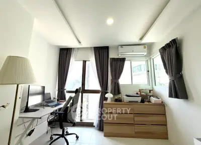 Modern study room with city view, featuring sleek desk and comfortable chair.