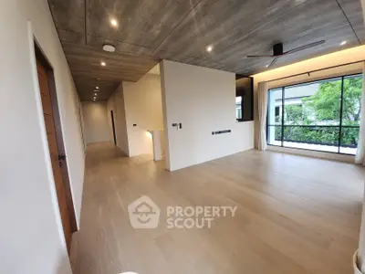 Spacious modern living room with wooden flooring and large window view.