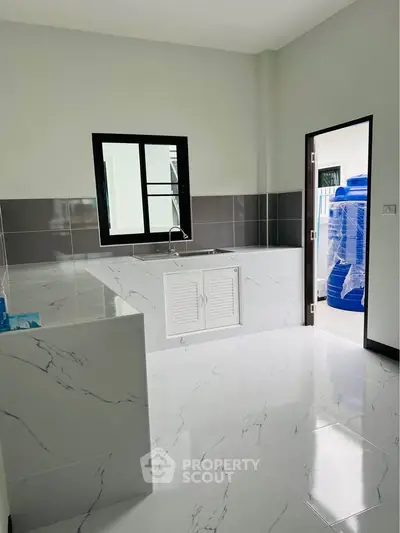 Modern kitchen with sleek marble countertops and tiled flooring, featuring a closed layout and ample natural light.