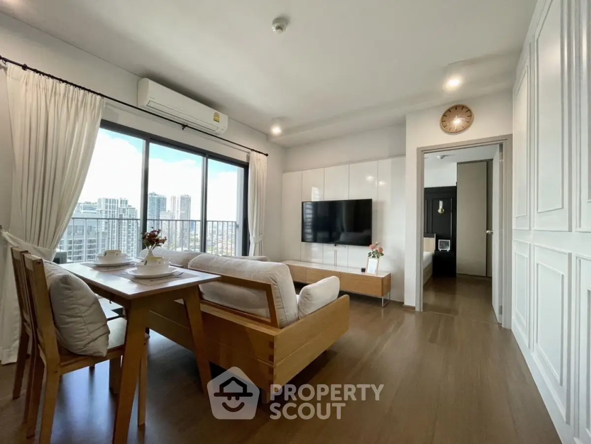 Modern living room with city view, wooden flooring, and sleek furniture