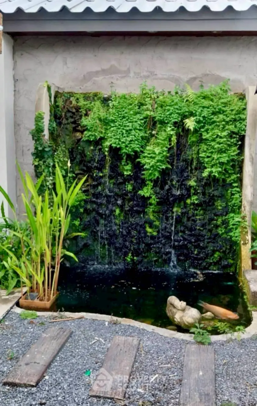 Charming garden water feature with lush greenery and serene pond, perfect for tranquil outdoor living.