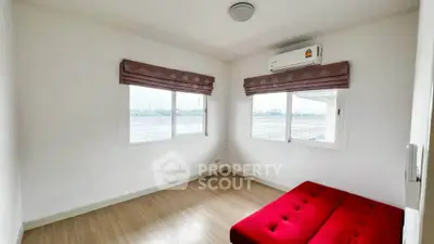 Bright bedroom with red sofa and large windows offering scenic views.