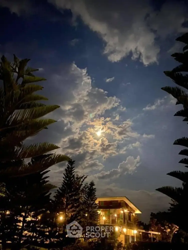 Stunning night view of a modern house with illuminated exterior under a moonlit sky.