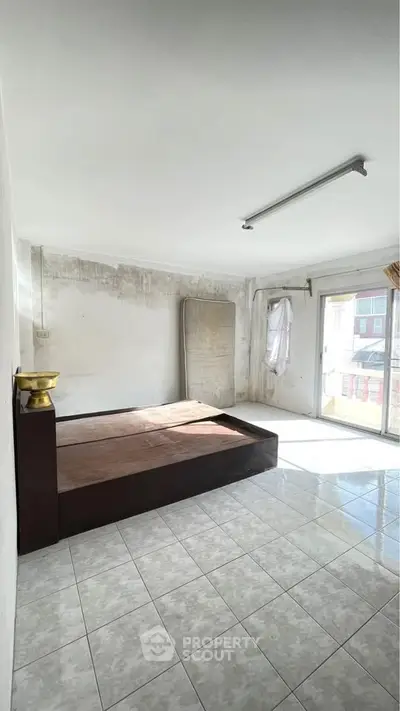 Spacious bedroom with natural light and tiled flooring, featuring a minimalist design.