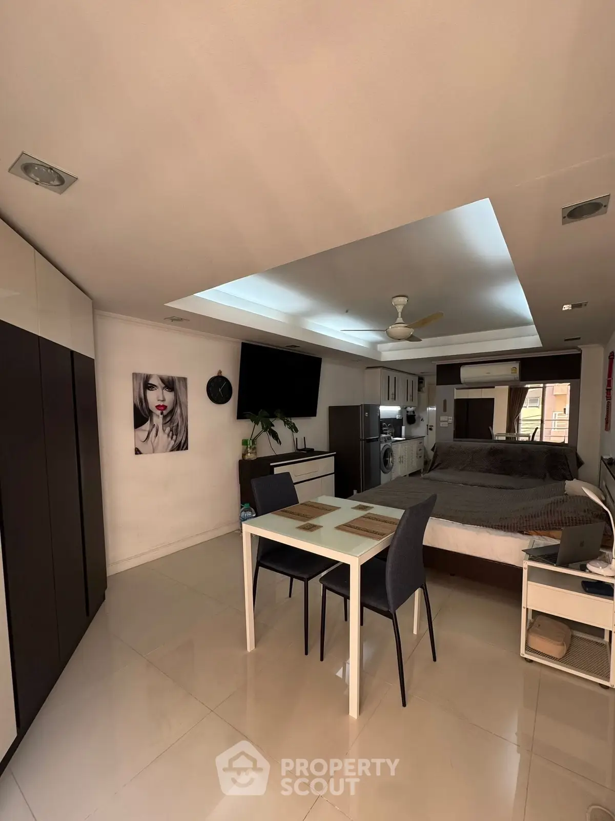Modern studio apartment with open layout, featuring a dining area, bed, and kitchen appliances.