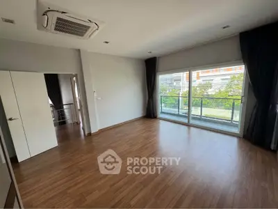 Spacious empty room with large windows and wooden flooring, perfect for customization.