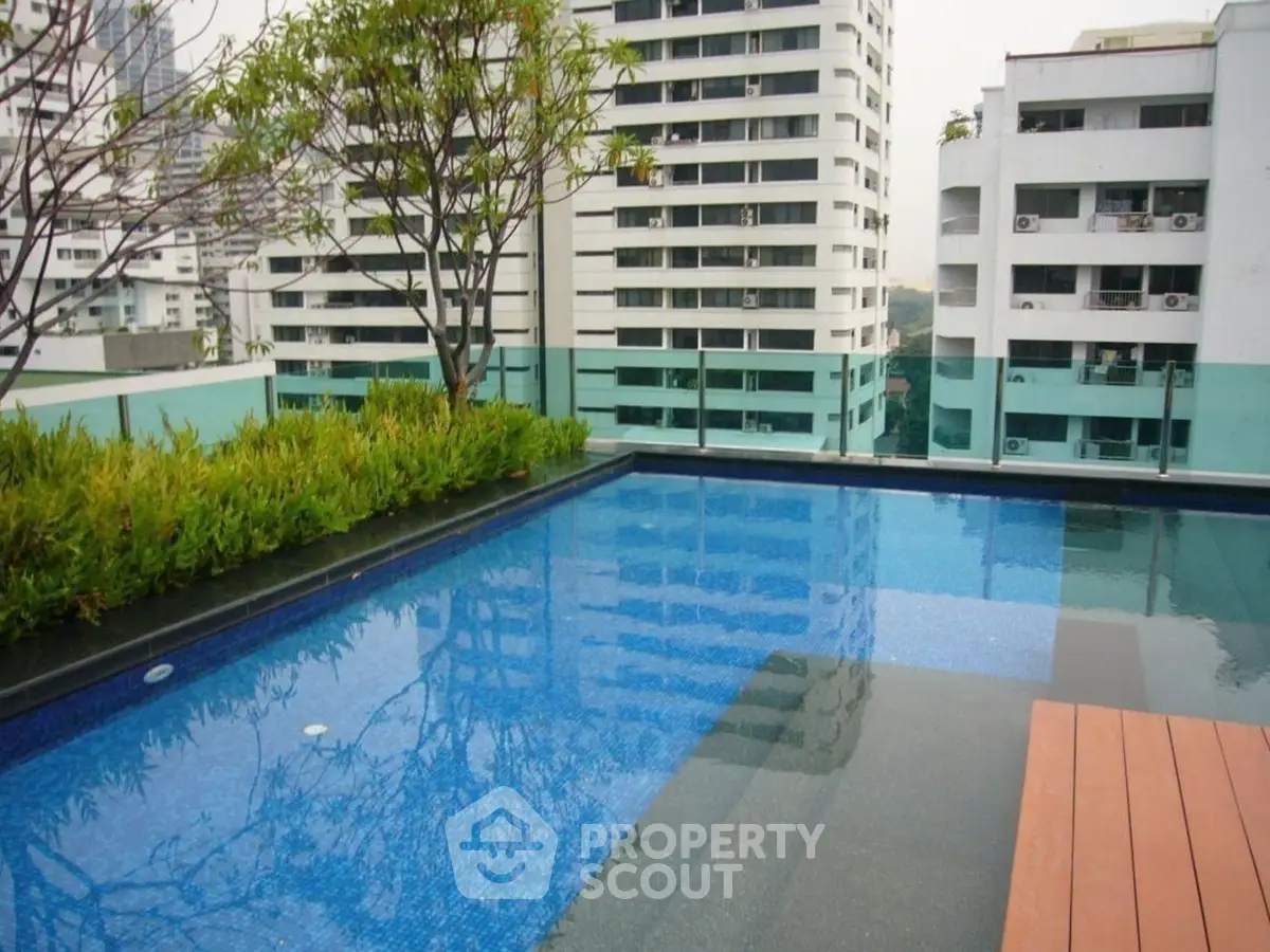 Stunning rooftop pool with cityscape views and lush greenery.