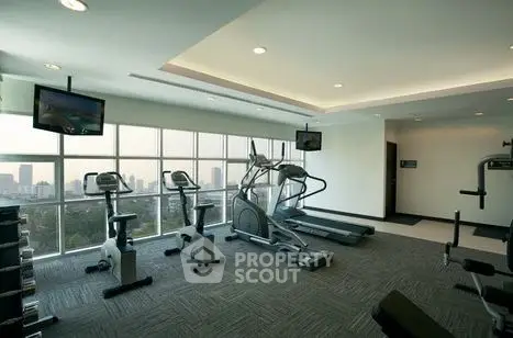 Modern gym with city view and state-of-the-art equipment in luxury apartment building.