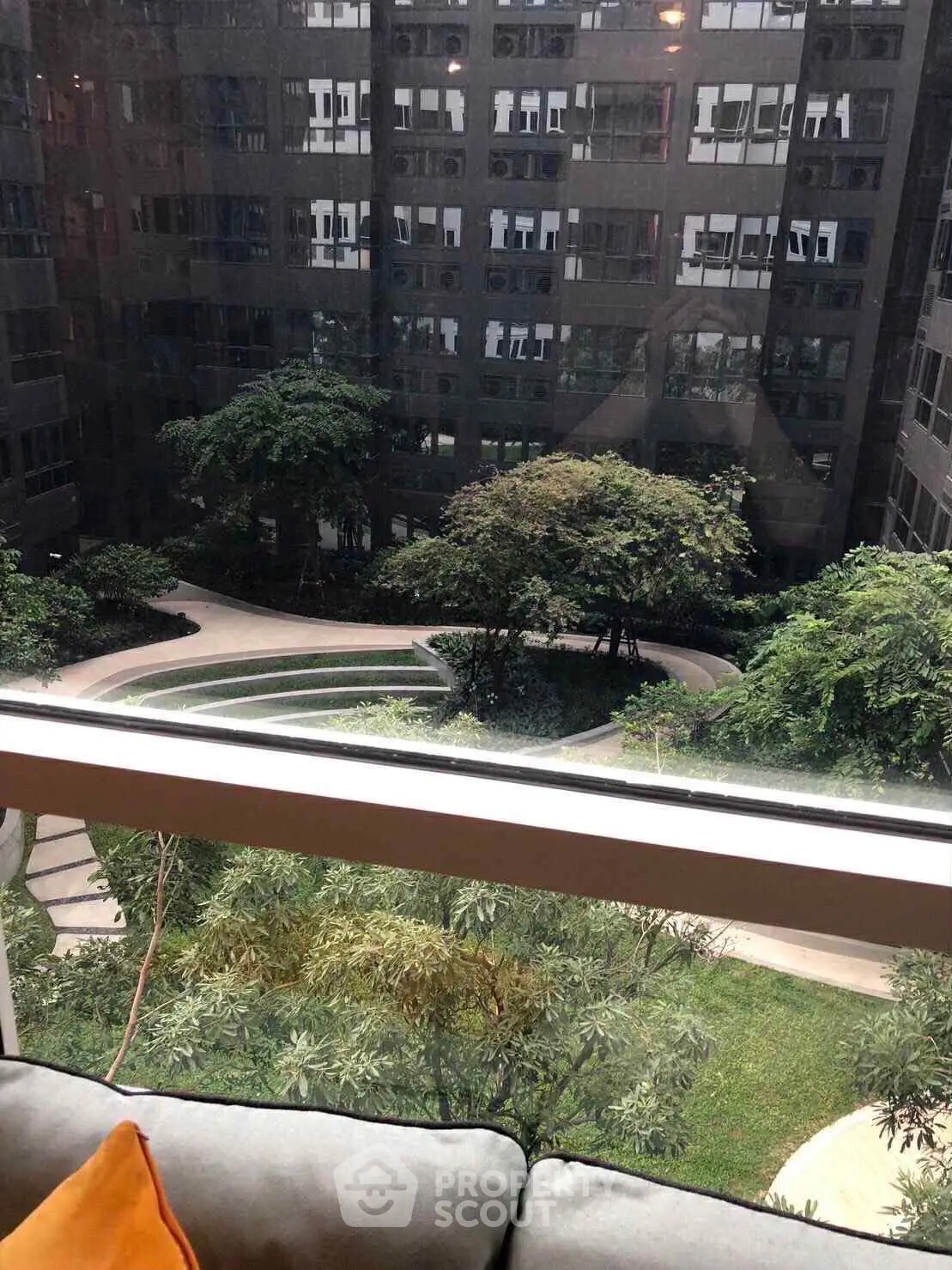 Stunning view of lush garden courtyard from high-rise apartment window.